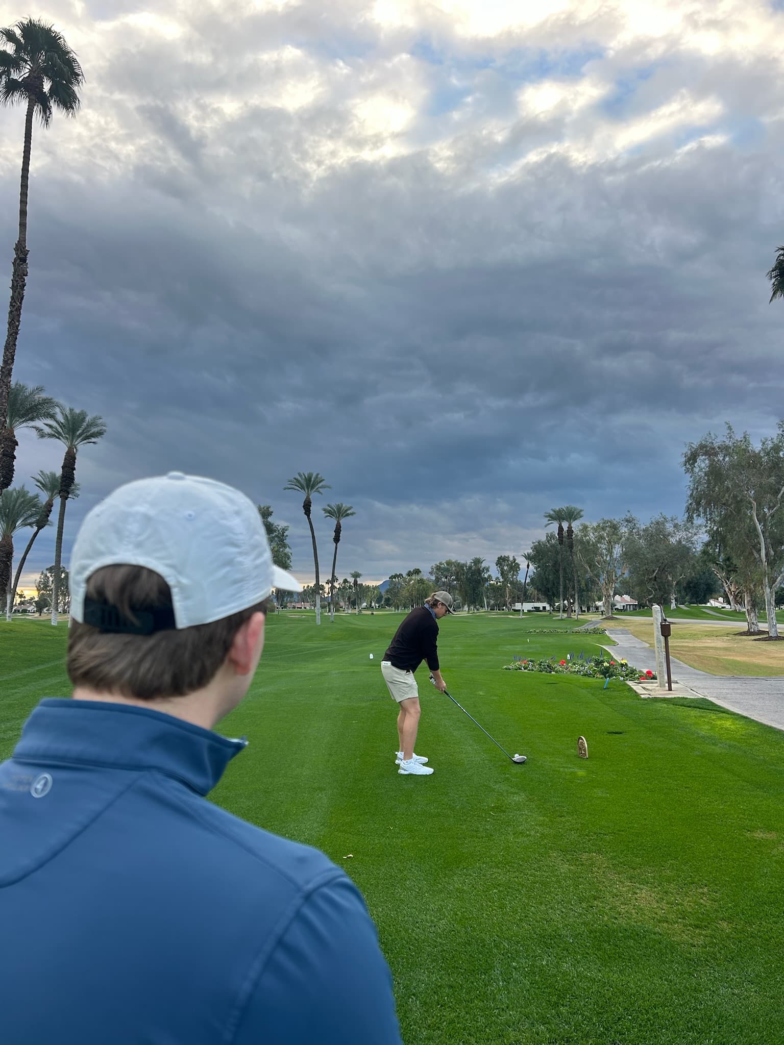 A player teeing off under storm clouds