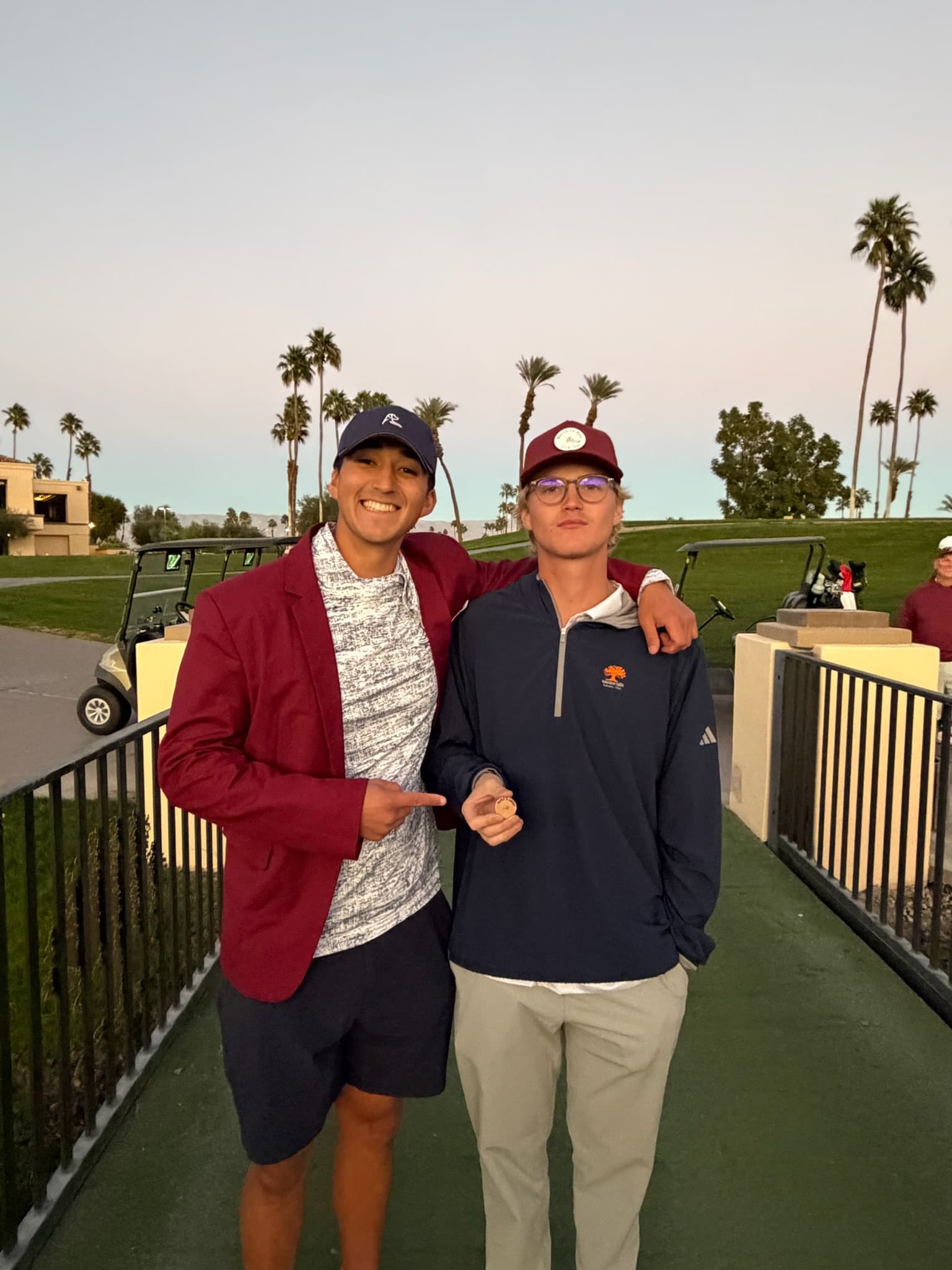 Two players posing with a tournament medallion